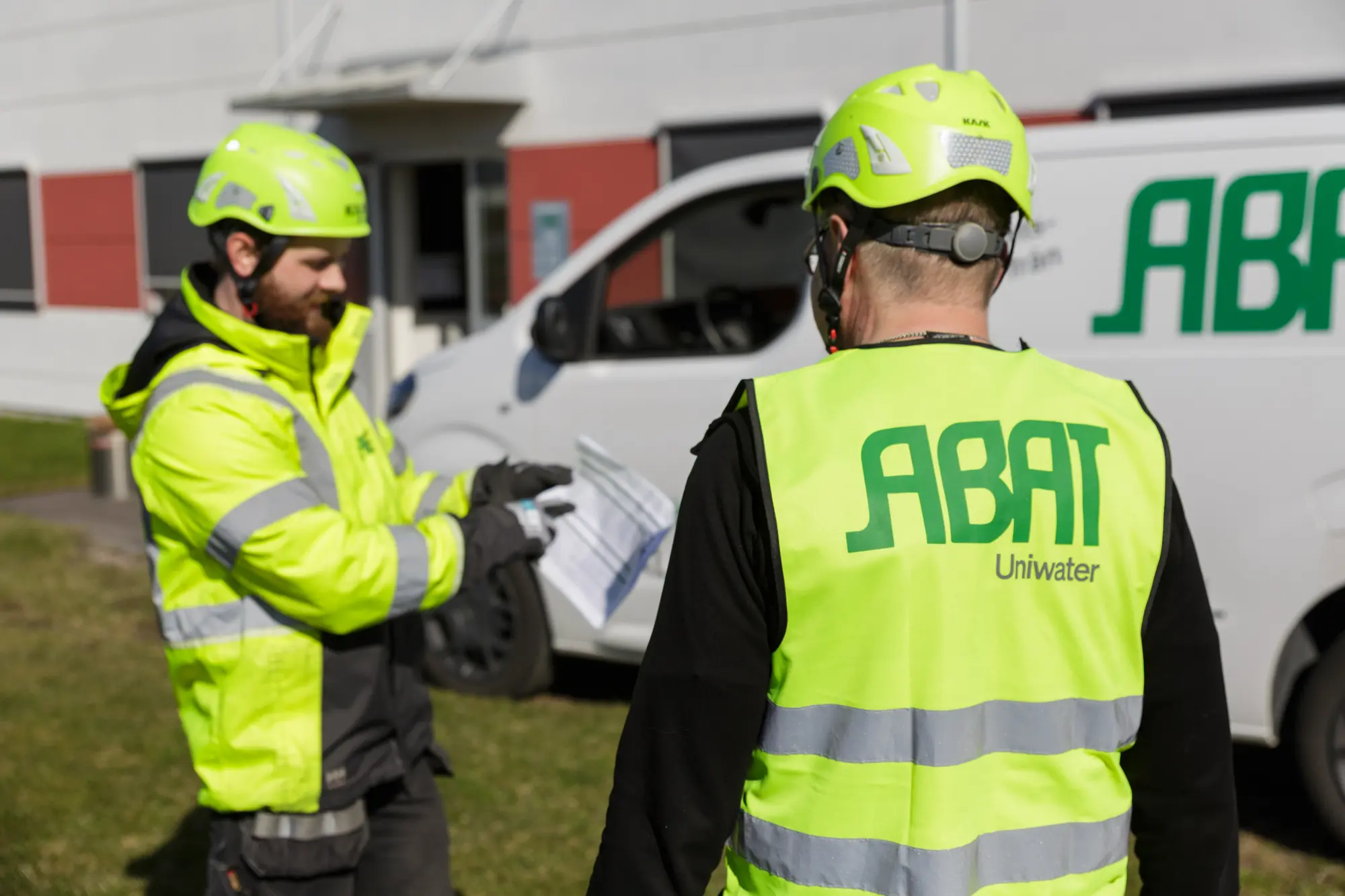 Två montörer i ABAT-västar går igenom underlag på plats