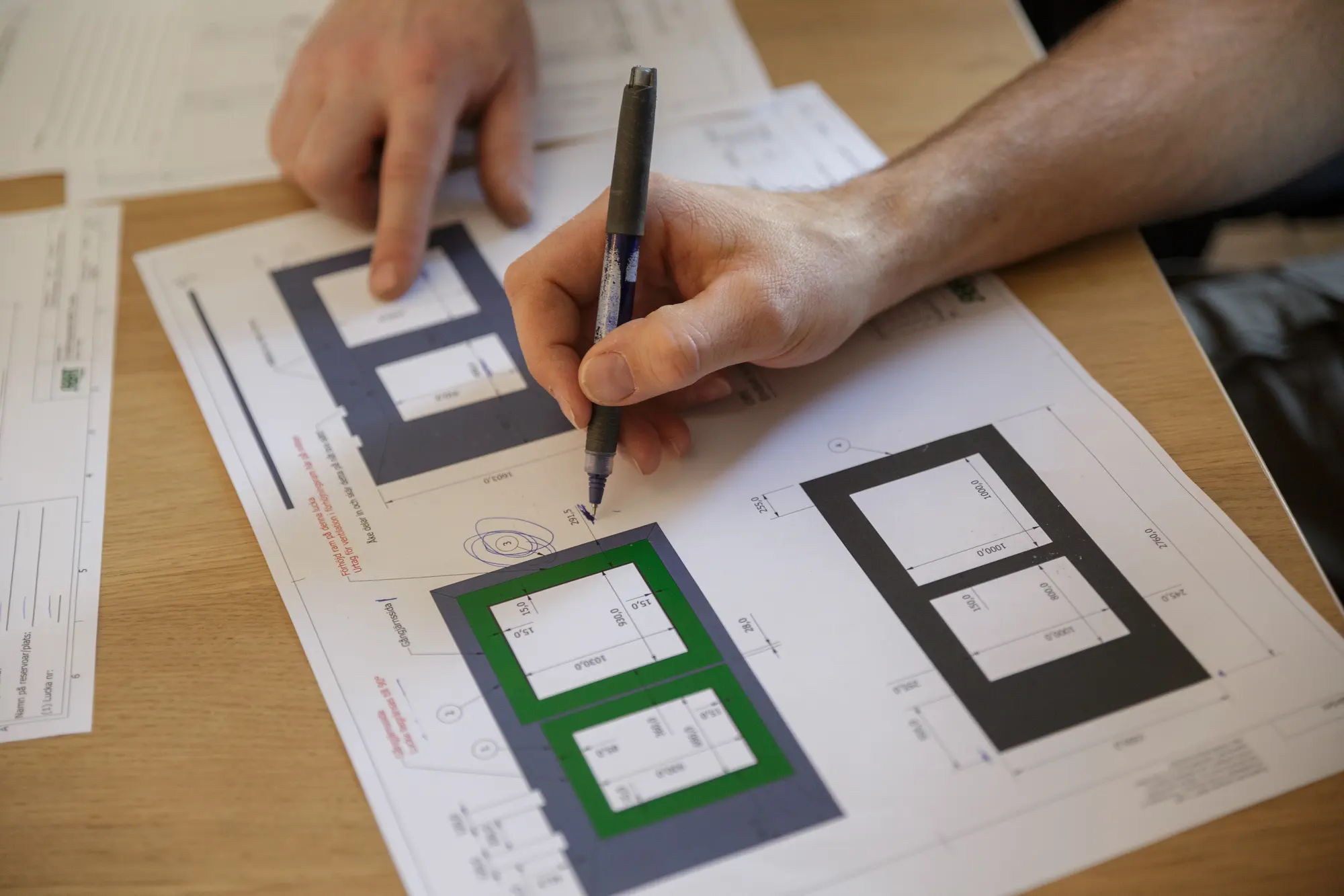 Hand som pekar med penna på en måttsatt ritning av en lucka